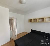 Bedroom in a two-room apartment with a bed, cabinet, and open door leading to the hallway.