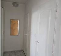 A hallway with a mirror in a 2-room apartment, white walls and doors, tiles on the floor.