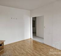 A room in a 2-room apartment with a wooden floor and white walls, with furniture.