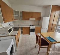 A kitchen in a 2-room apartment with wooden cabinets and a dining table.