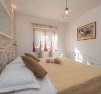 Bedroom in a family house with an iron bed, a painting on the wall, and stone cladding.