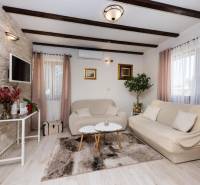 Living room of a family house, comfortable sofas, TV, greenery, decorations, wooden beams.