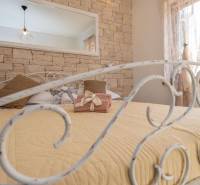 A bedroom in a family house with a decorated metal bed and a brick wall.