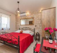 A bedroom in a family house with a metal bed, stone walls, and red accessories.
