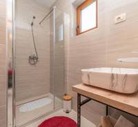 A bathroom in a family house with a sink, a shower, and a window.