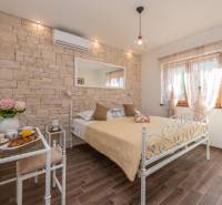 Bedroom with a stone wall, metal bed, and a table with drinks in a family house.