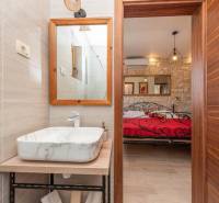 Bathroom with a sink, mirror, and a view into the bedroom in a family house.