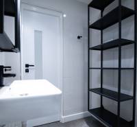 A minimalist bathroom with a white sink, black elements, and shelves in a 3-room apartment on Boriny Street.