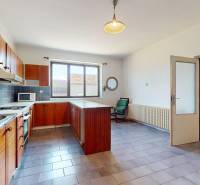 A kitchen in a family house with wooden cabinets, a large window, and a microwave oven.