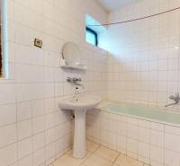 A bathroom in a family house with a bathtub, a sink, and ceramic tiles.