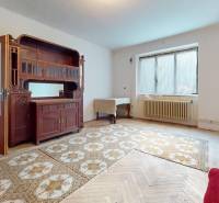 A room in a family house with a carpet, an antique wardrobe, and a table by the radiator.
