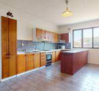 A kitchen in a family house with wooden cabinets, a sink, a stove, and a window.