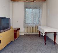 A room in a family house with an older television, a table, and a radiator under the window.