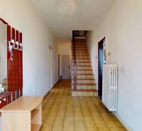 A hallway in a family house with a wooden staircase, a mirror, and a wall hanger.