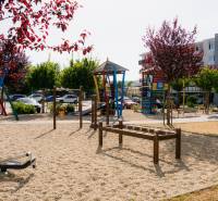 A children's playground in Trenčín with colorful climbing frames and trees, suitable for family time.