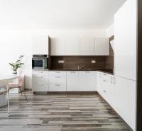A kitchen in a 2-room apartment with a white kitchen unit and wooden floor.