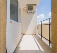 Balcony of a 2-room apartment in Trenčín with a view of the sunny blue sky.