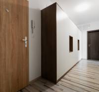 Narrow hallway corridors with wooden and white cabinets in a 2-room apartment.