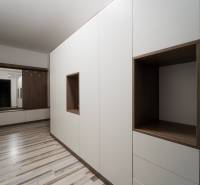 An entrance hallway in a 2-room apartment with white and wooden cabinets.