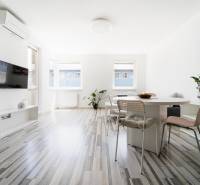 A bright living space with large windows and a dining table in a 2-room apartment.
