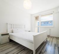A bright bedroom with a white bed and furniture in a two-room apartment.