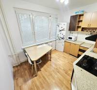 A kitchen with a stove, refrigerator, and table in a 3-room apartment.