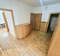 The hallway of a 3-room apartment with wooden floors and furniture, view towards the room.