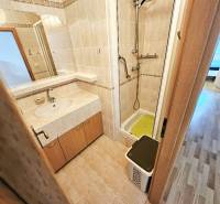 Bathroom with a shower in a 3-room apartment, light tiles and a mirror.