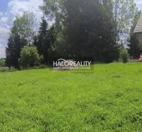 A plot in Malatíny with a grassy area and a wooden house, ideal for living.