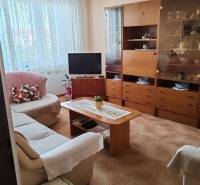 Living room with a sofa, television, and wooden cabinet in a three-room apartment.