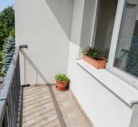 A balcony with flower pots belonging to a 3-room apartment, view of greenery.