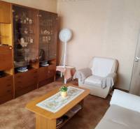 Living room in a three-room apartment with wooden furniture and a white armchair.