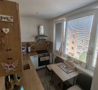 A kitchen in a 3-room apartment with a wooden cabinet, dining table, and appliances.