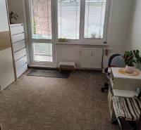 A room in a 3-room apartment with a carpet, furniture, and large windows with a view.