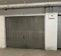 Metal gate in the garage with piping and an electrical panel on the wall.