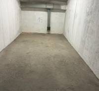 Closed garage space with a concrete floor and white walls, number 19, pipes on the ceiling.