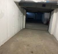 A view of the internal access corridor in the garages with visible pipes and ceiling.
