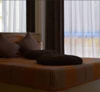 A bed with brown bedding and pillows in a 2-room apartment.