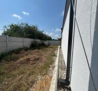 A family house in Žihárec with a garden, fencing, and a blue sky in the background.