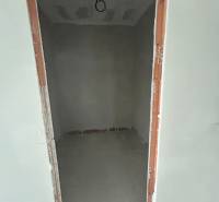 An empty room under construction in a family house with bare plaster walls.