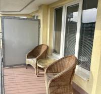 A balcony of a 2-room apartment with two rattan chairs and a table.