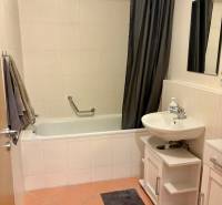 A bathroom in a 2-room apartment with a bathtub, a sink, and a shower curtain.