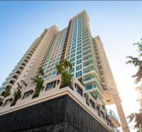 Apartment construction in Pattaya with a tall skyscraper surrounded by palm trees and a blue sky.