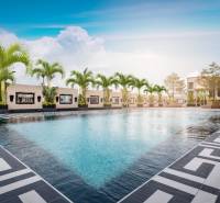 A pool with palm trees under construction in an apartment complex in Pattaya under the blue sky.