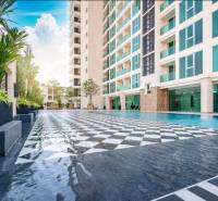 The construction of apartments in Pattaya includes a swimming pool, a high-rise building, and green plants.