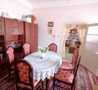 Dining room in a family house with antique furniture, a floral carpet, and light decor.