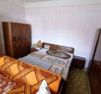 Bedroom in a family house with a bed, wardrobes, and paintings on the wall.