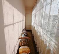 A narrow hallway with lace curtains and an armchair in a family house.