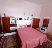 A bedroom with wooden furniture and pink bedding in a family house.