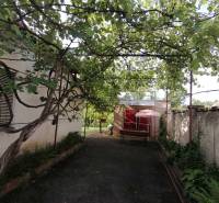 A family house in Hrkovce with a bench under climbing plants in the garden.